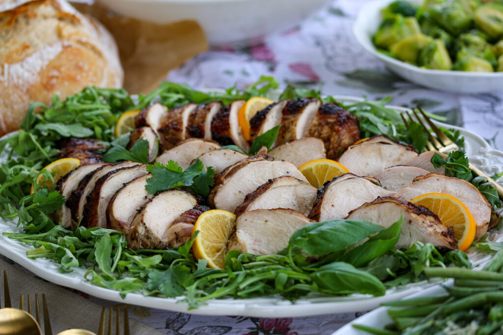 Smoked Chicken Breasts are sliced and served on a beautiful platter of arugula and basil. 