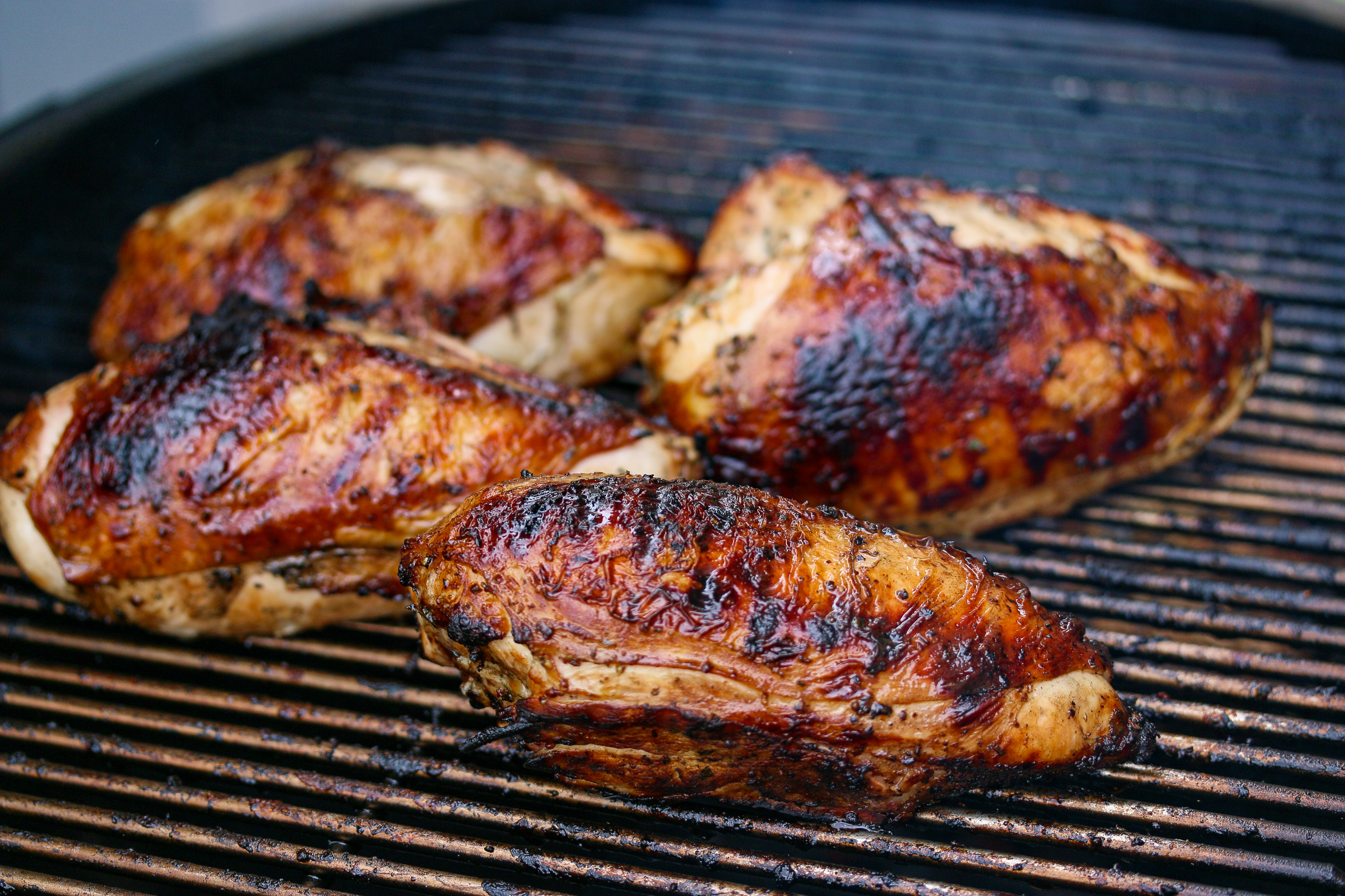 Amber colored chicken have completed cooking but are still on the grill. 
