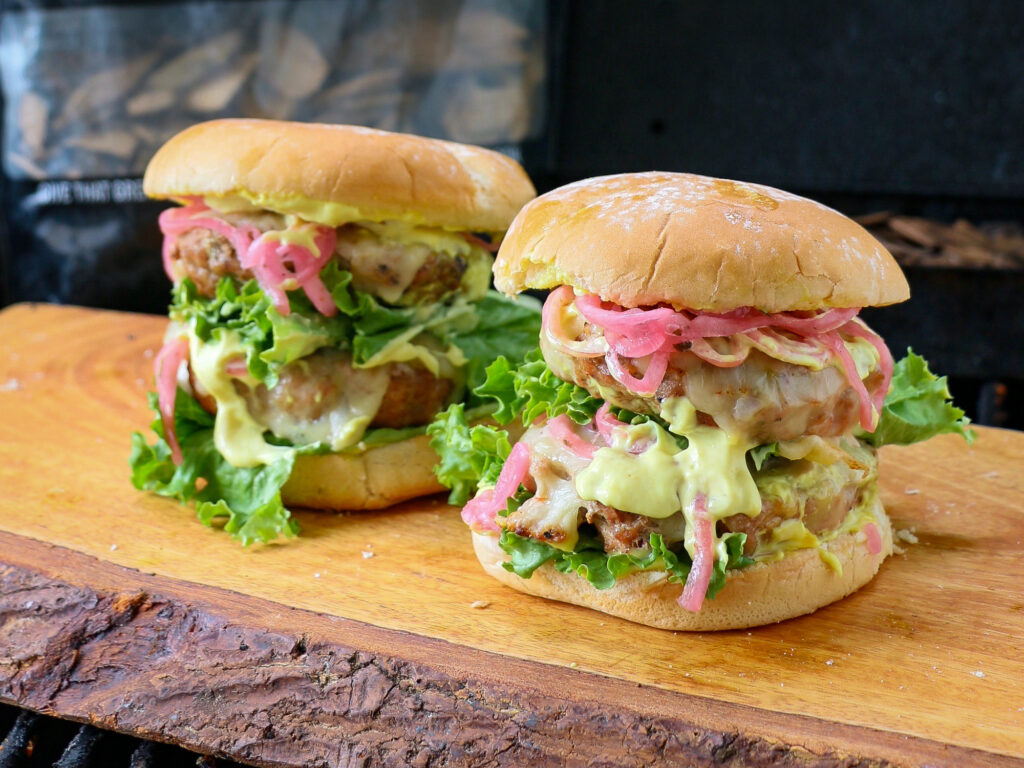 To show a pork burger with mustard and pickled red onions.
