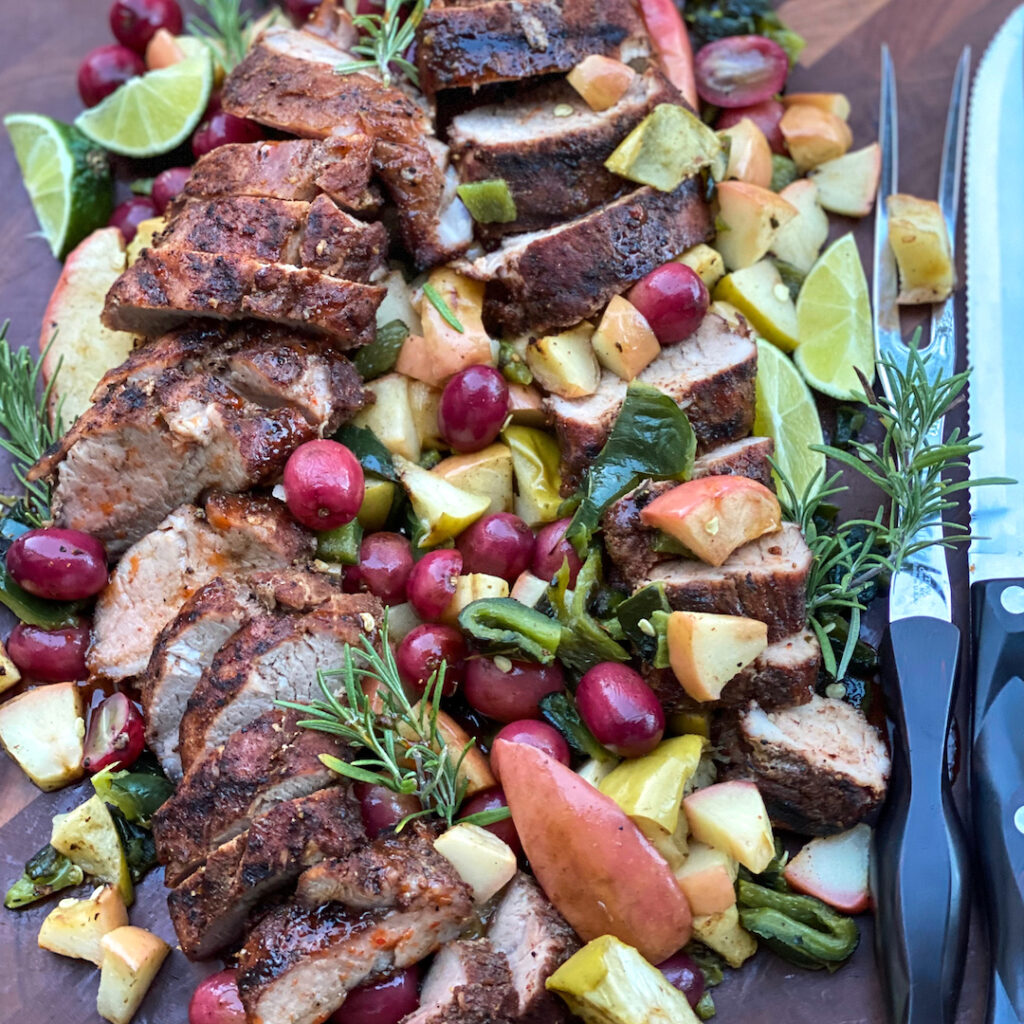 A beautifully platter of Apple Smoked Five Spice Pork Tenderloin with Roasted Grapes, Grilled Apple, and Charred Poblano.