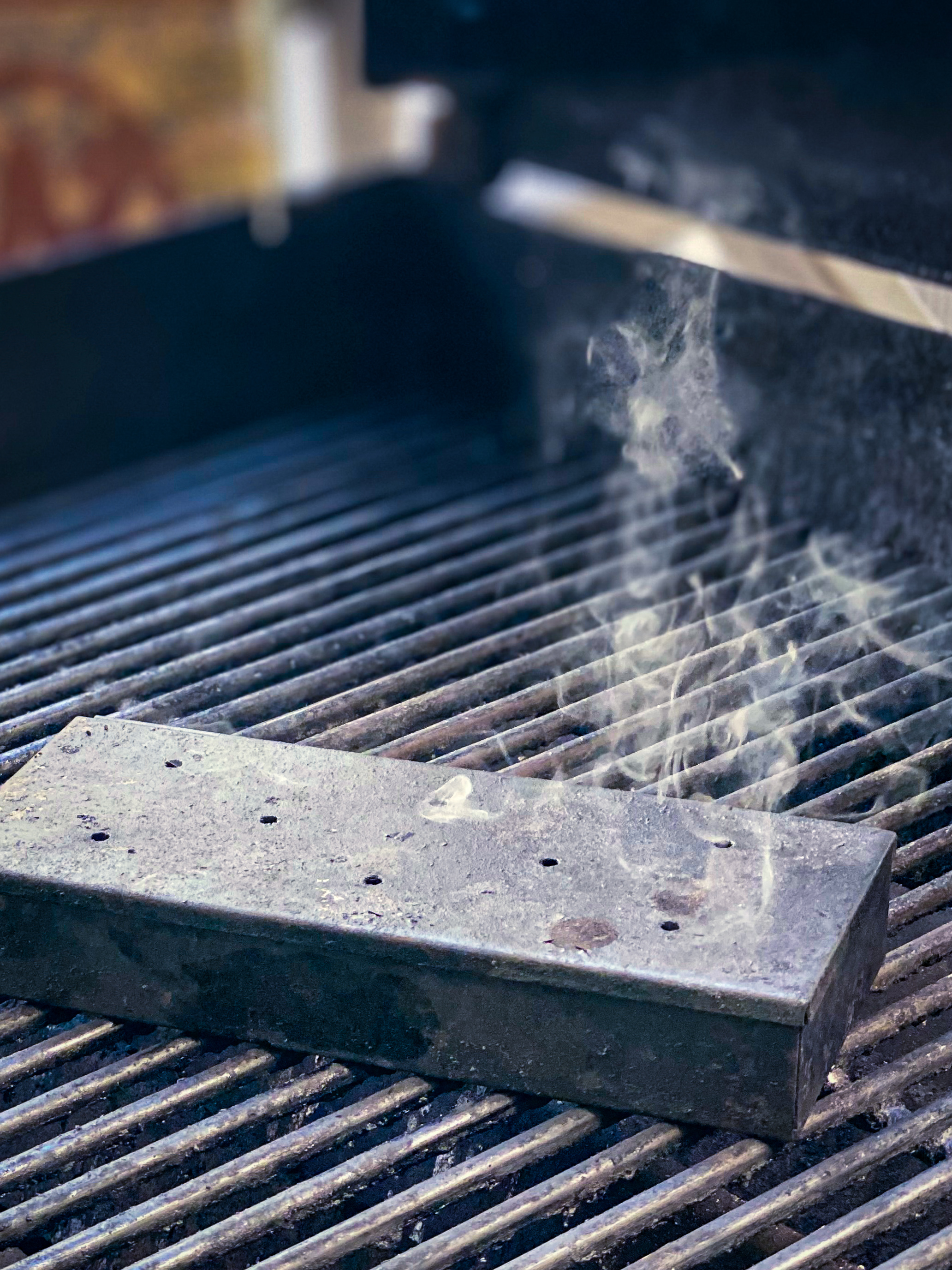 Smoke has begun to stream from a smoker box on gas grill. 
