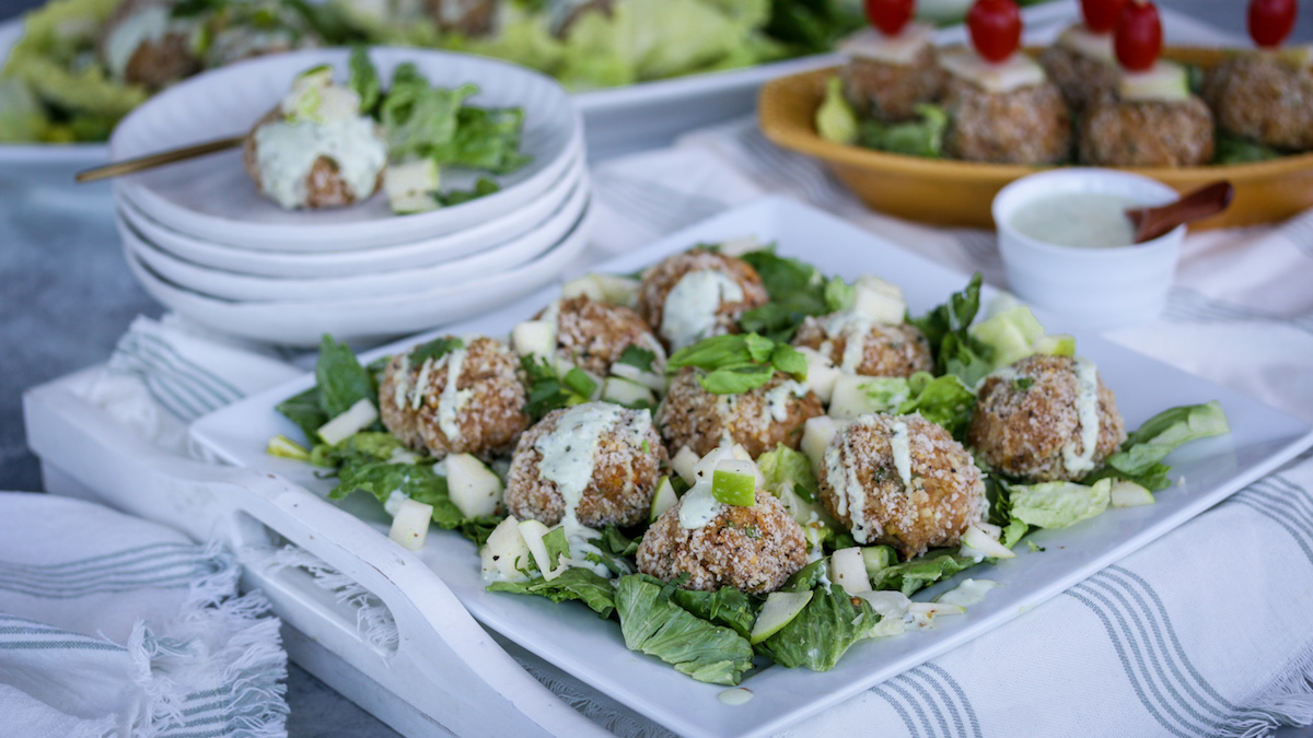 A platter of chicken meatballs on a bed of lettuce.