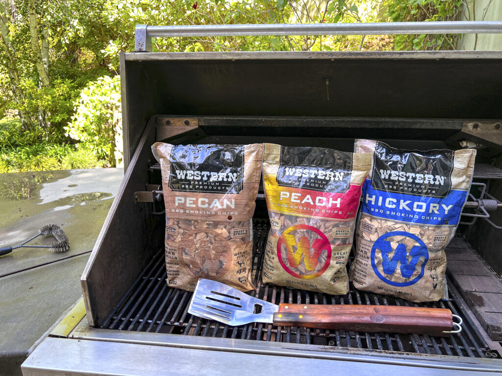 Three bags of Western BBQ Smoking Chips sit on a clean grill. 