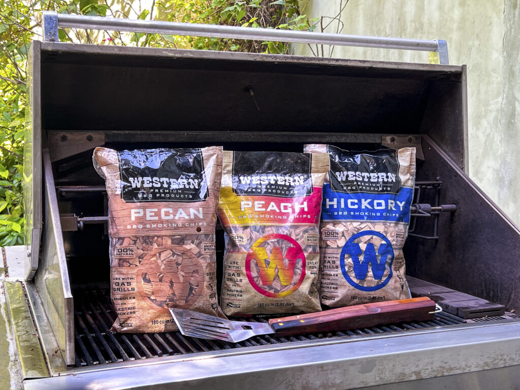 Three bags of Western BBQ Smoking Chips sit on a recently cleaned grill.