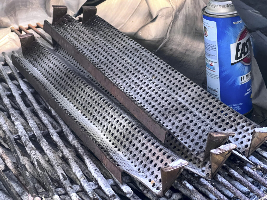 Spray grill cleaner on grates and flame tamers.