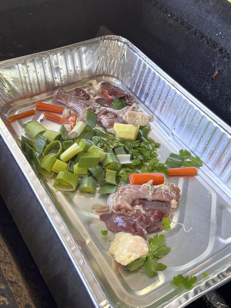 An aluminum pan is used as a drip pan. This pan has leeks, giblets, carrots, and celery. 