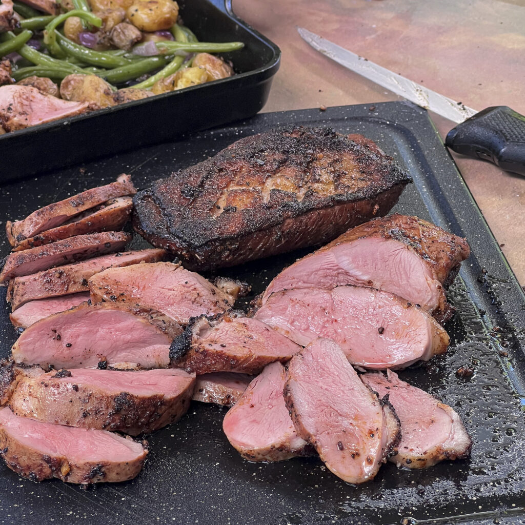 A cutting board with perfectly pink sliced duck breast.