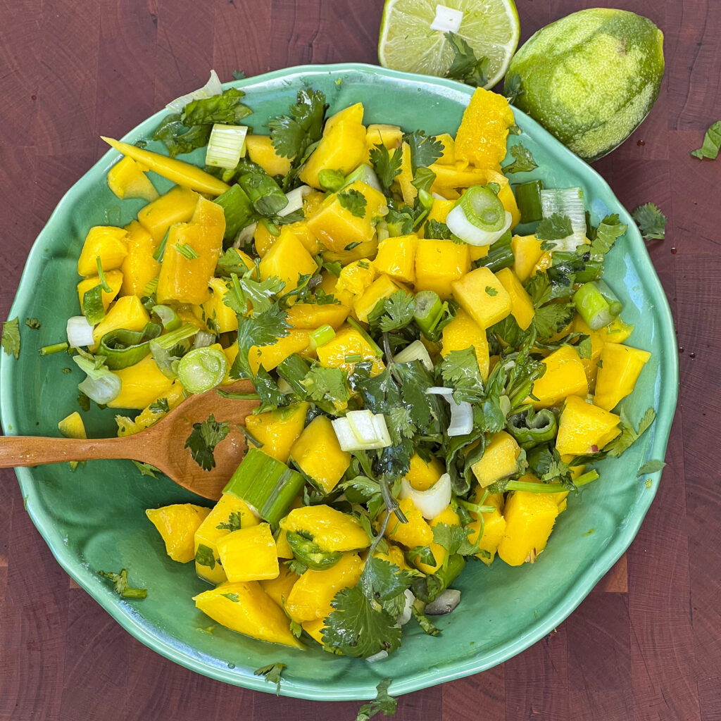 A bowl of chopped mango and cilantro is in a pretty green bowl to show a side dish for smoked duck.