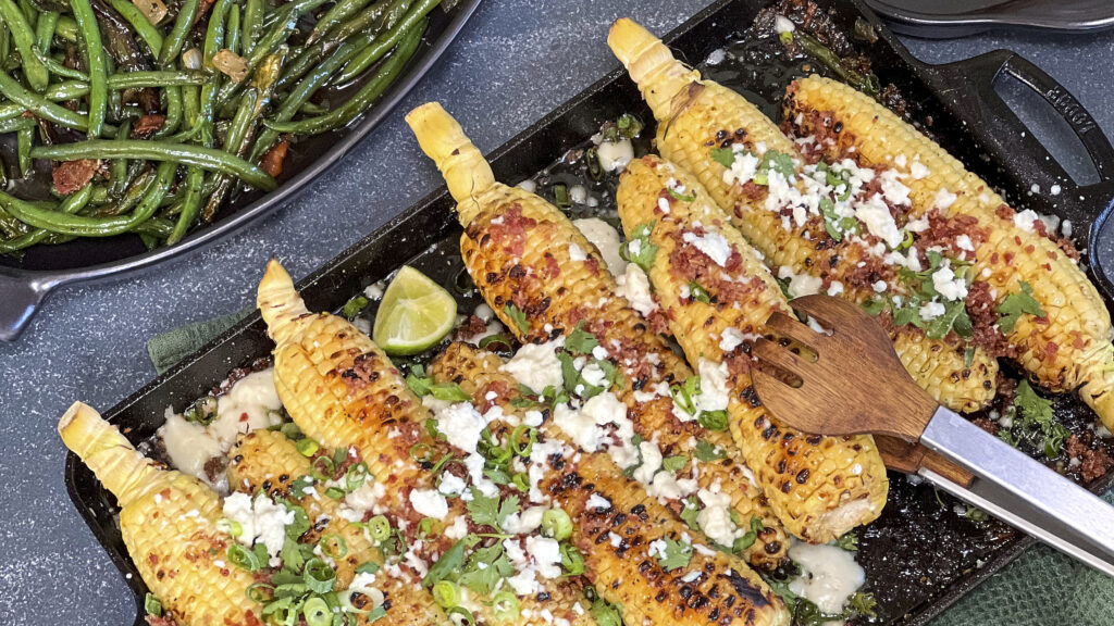 Corn on the cob on the grill with queso fresco, cilantro, and scallions. 
