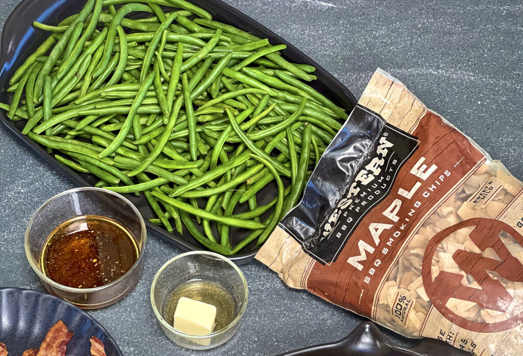 Western BBQ Maple Smoking Chips are next to a pan of blanced green beans. A maple glaze and 2 tablespoons butter in the scene.