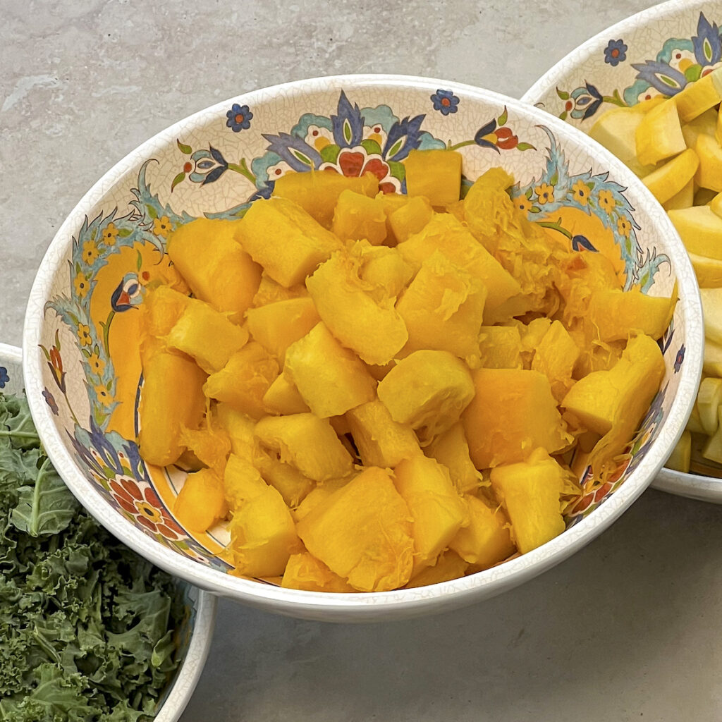 Pumpkin is cut into cubes and in a bowl. 