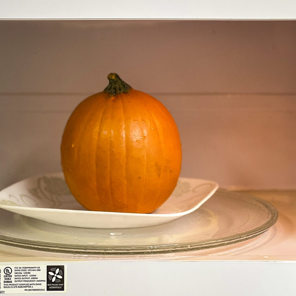 A pumpkin is in the microwave ready to be par-cooked. 