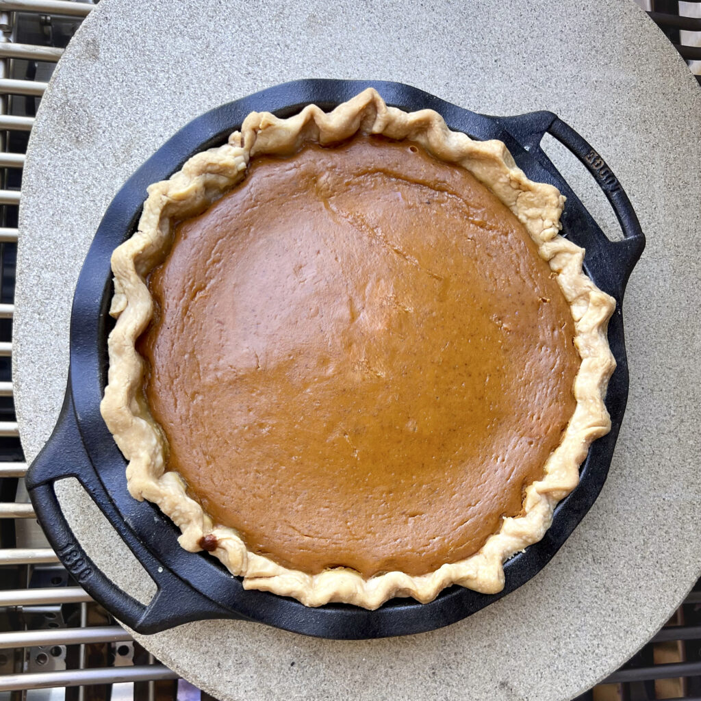 An overhead view of a smoked pumpkin pie on the grill. 