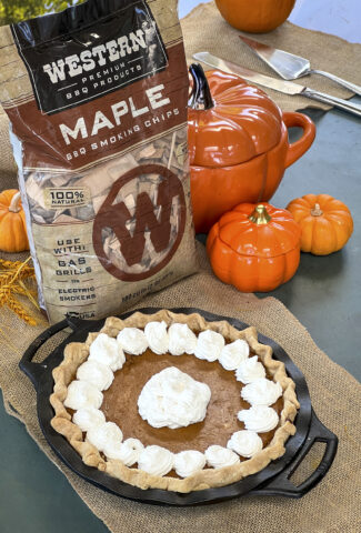 A smoked pumpkin pie with whipped cream is next o a bag of Western BBQ Maple Smoking Chips.