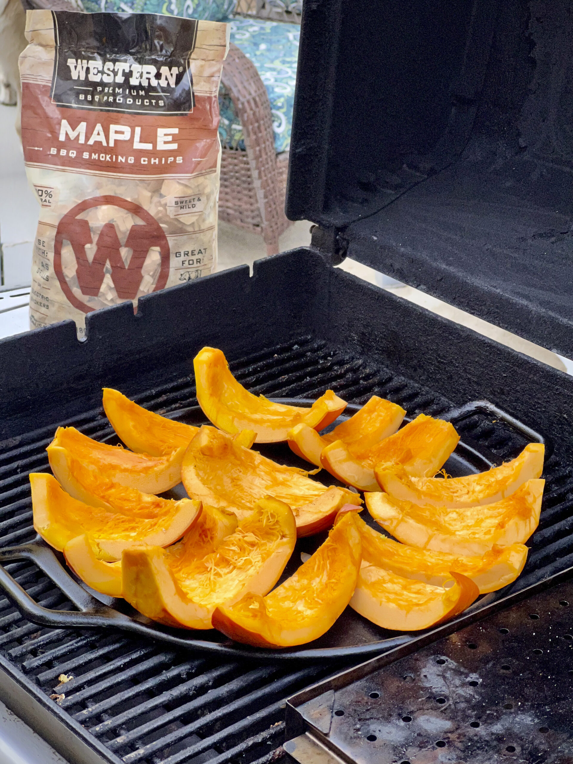 Slices of pumpkin are on the grill being smoked by maple smoking chips.