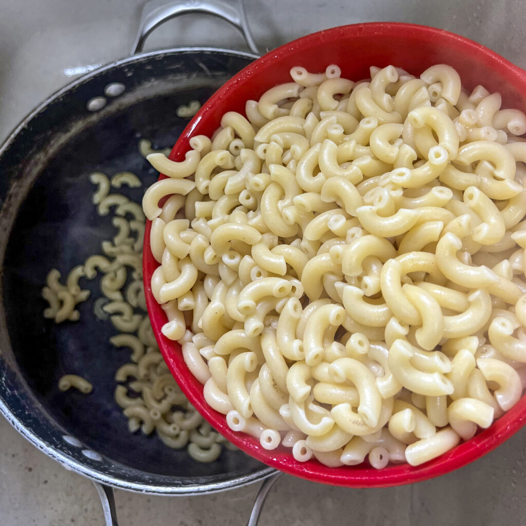 A colander filled cooked elbow macaroni. 