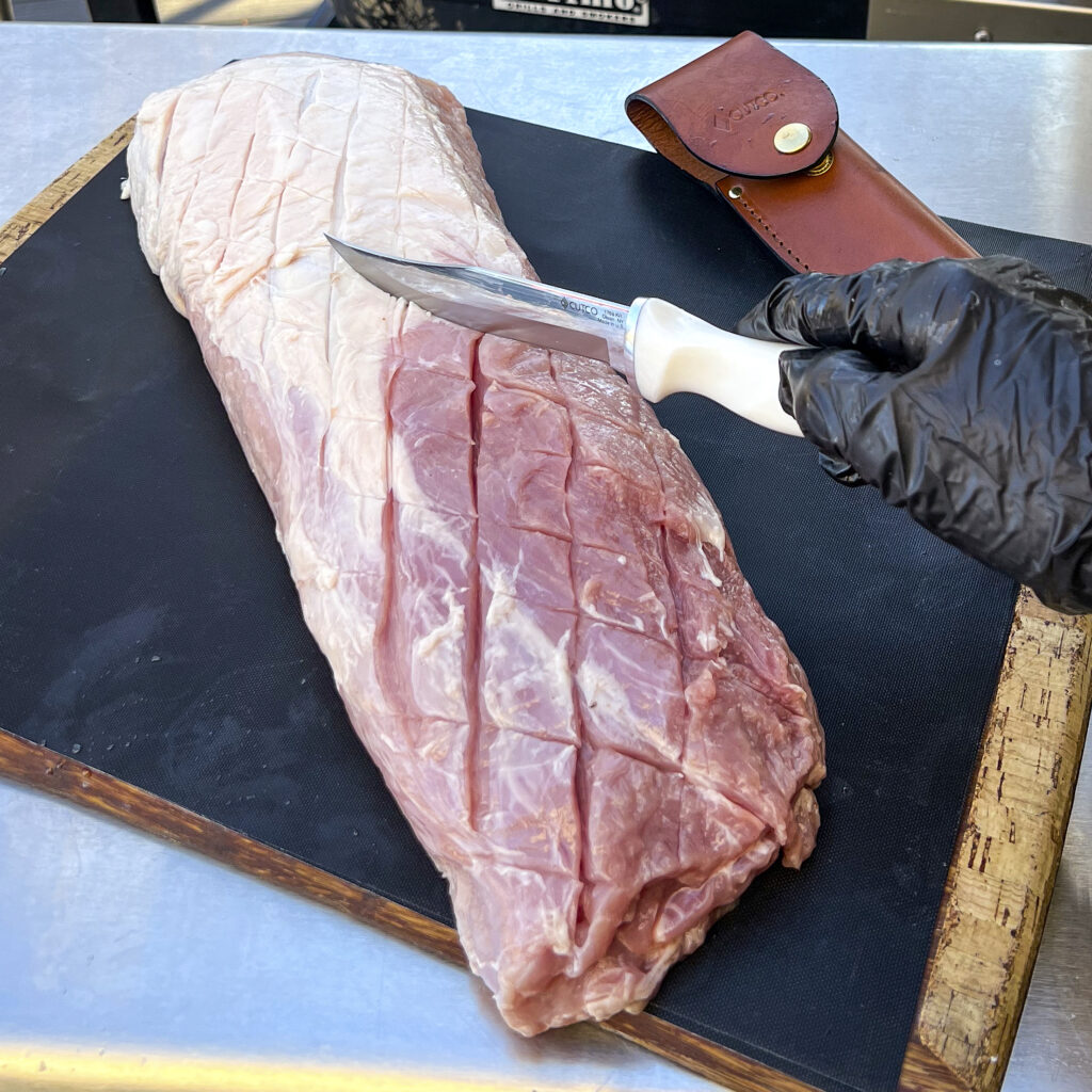 Scoring a pork loin with a sharp knife.