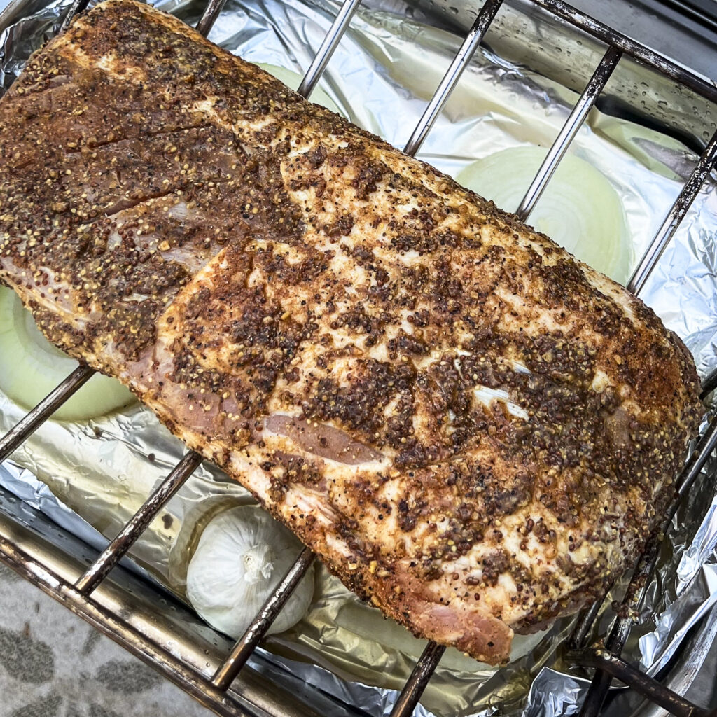 A partially smoked pork loin in a rack. 