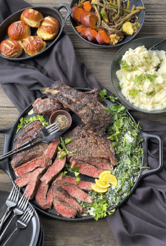 A cast iron platter with cut ribeye steaks and parmesan spinach.