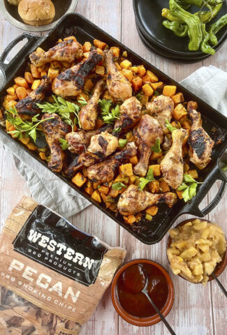 A cast iron pan roasted butternut squash and smoked chicken drumsticks. A bag of Western BBQ Pecan Smoking Chips are in teh photograp