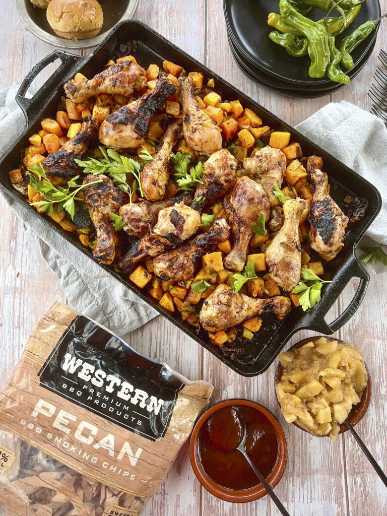 Smoked Chicken Drumsticks are on a cast iron pan with butternut squash. 