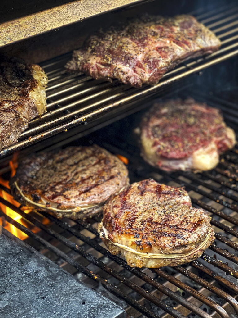 Hickory Smoked Ribeye Steaks are grilled on both sides and ready to be taken from the grill.