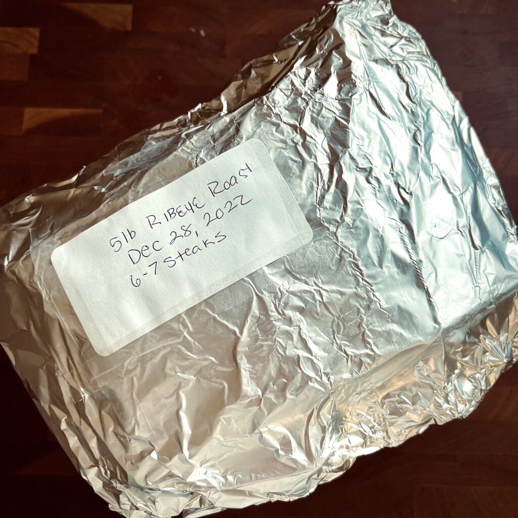 A ribeye roast that has been wrapped in foil and marked for the freezer.