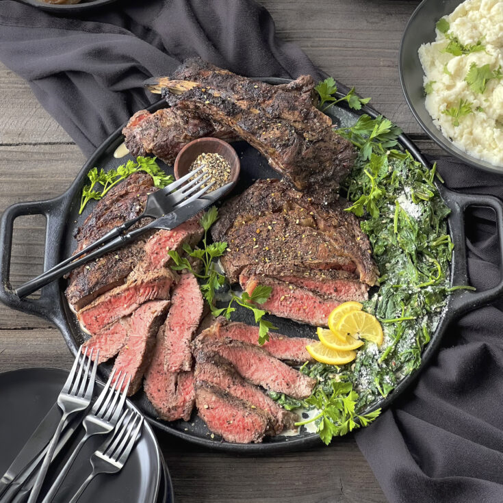 Ribeye Steaks on a serving platter with spinach.