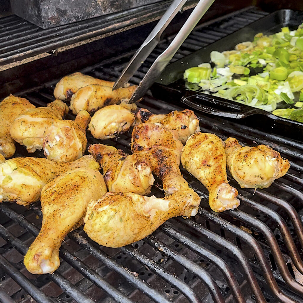 Chicken Drumsticks are being smoked over indirect heat on a grill. 