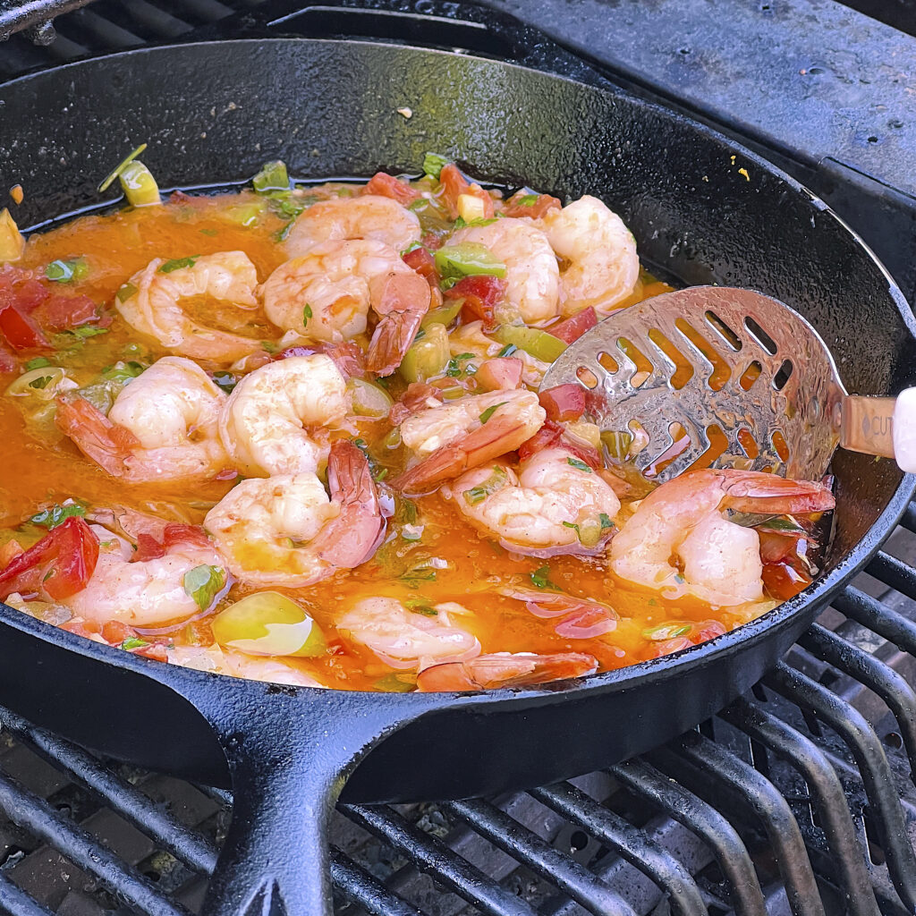 A skillet on the grill with shrimp. 