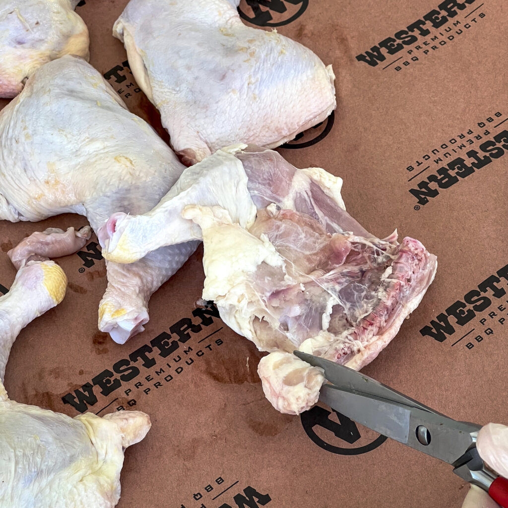 Scissors cutting off the chicken tail before seasoning. 