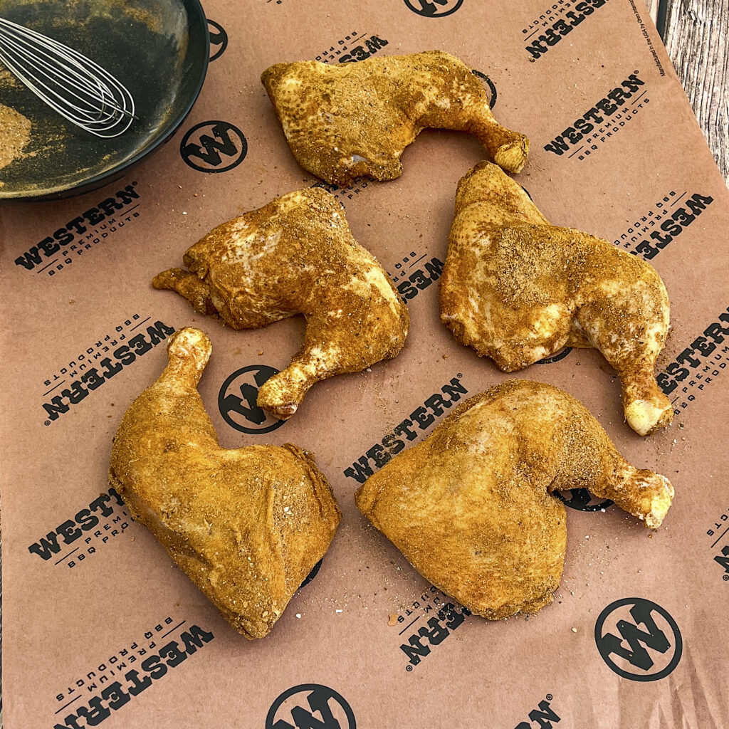 Seasoned chicken hindquarters are air drying on a piece of Western BBQ butcher paper. 