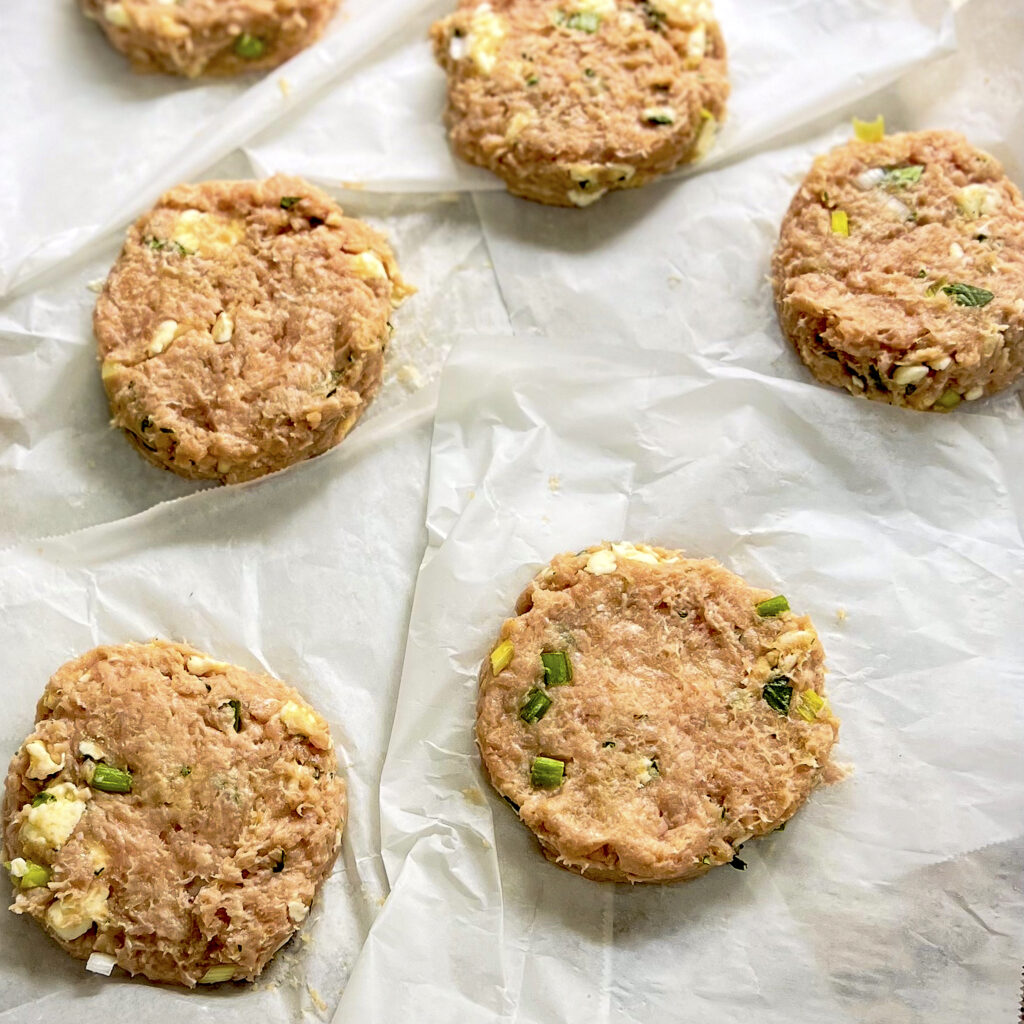 Ground chicken patties are dotted with butter green onion, and cilantro 