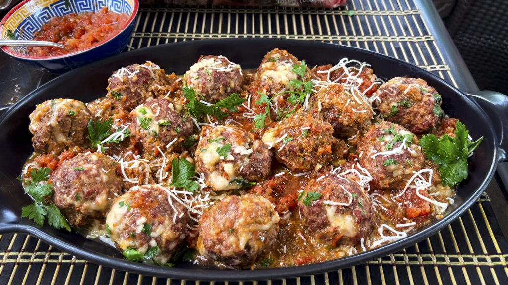 Meatballs are on a platter with a marinara on it. 