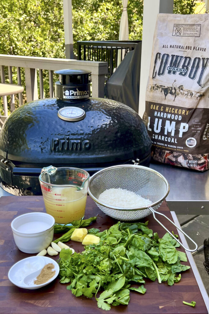 A grill and a bag of Cowboy Charcoal are in the back of a chopping board that holds the ingredients for Hawaiian Rice. 
