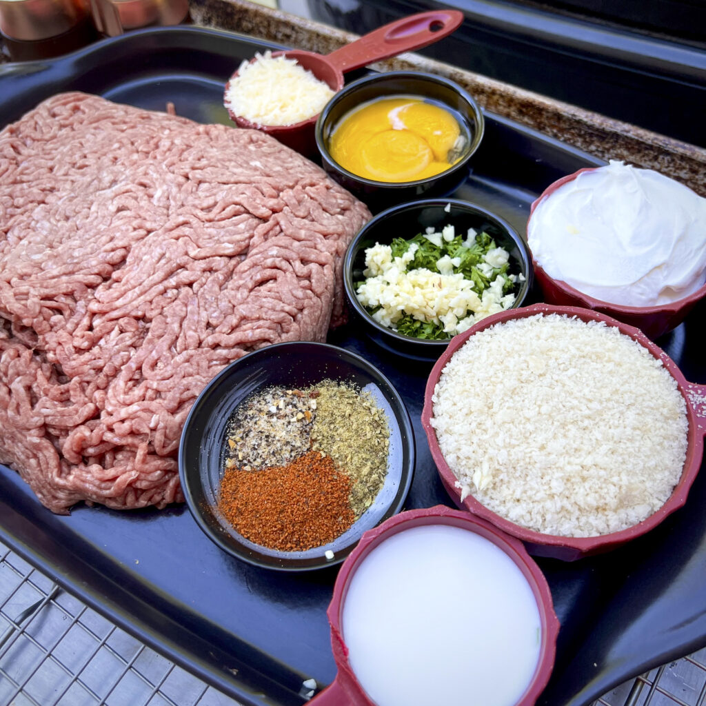 A platter with meat to make meatballs. Ground beef, 3 spices, garlic and\parsley, ricotta, Parmesan