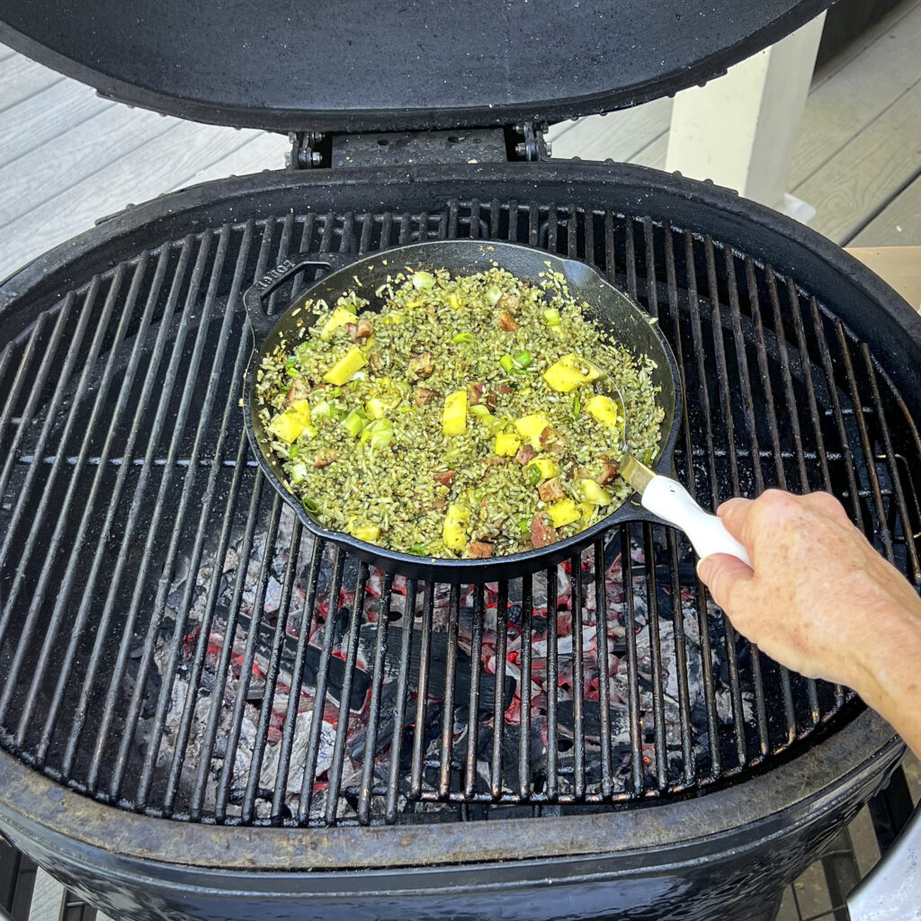The grill has a skillet of green rice and pineapple. 