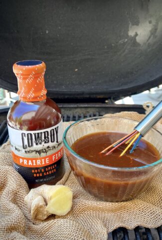 A bottle of Cowboy Brand Prairie Fire BBQ sauce with gingerroot and a bowl of Korean BBQ Sauce.