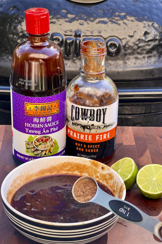 A bottle of Hoisin is next to a bottle of Cowboy BBQ Sauce.