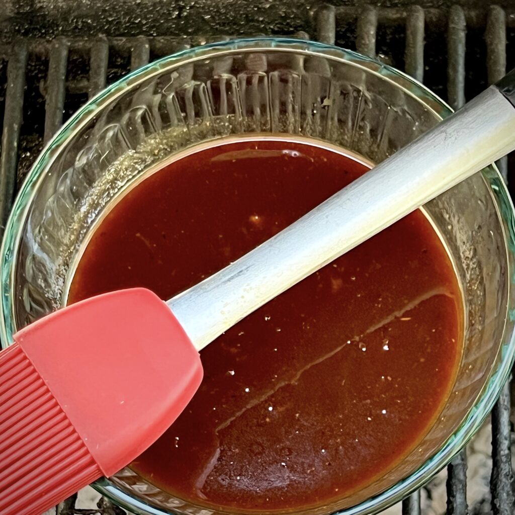 Homemade BBQ sauce in a bowl with a culinary brush. 