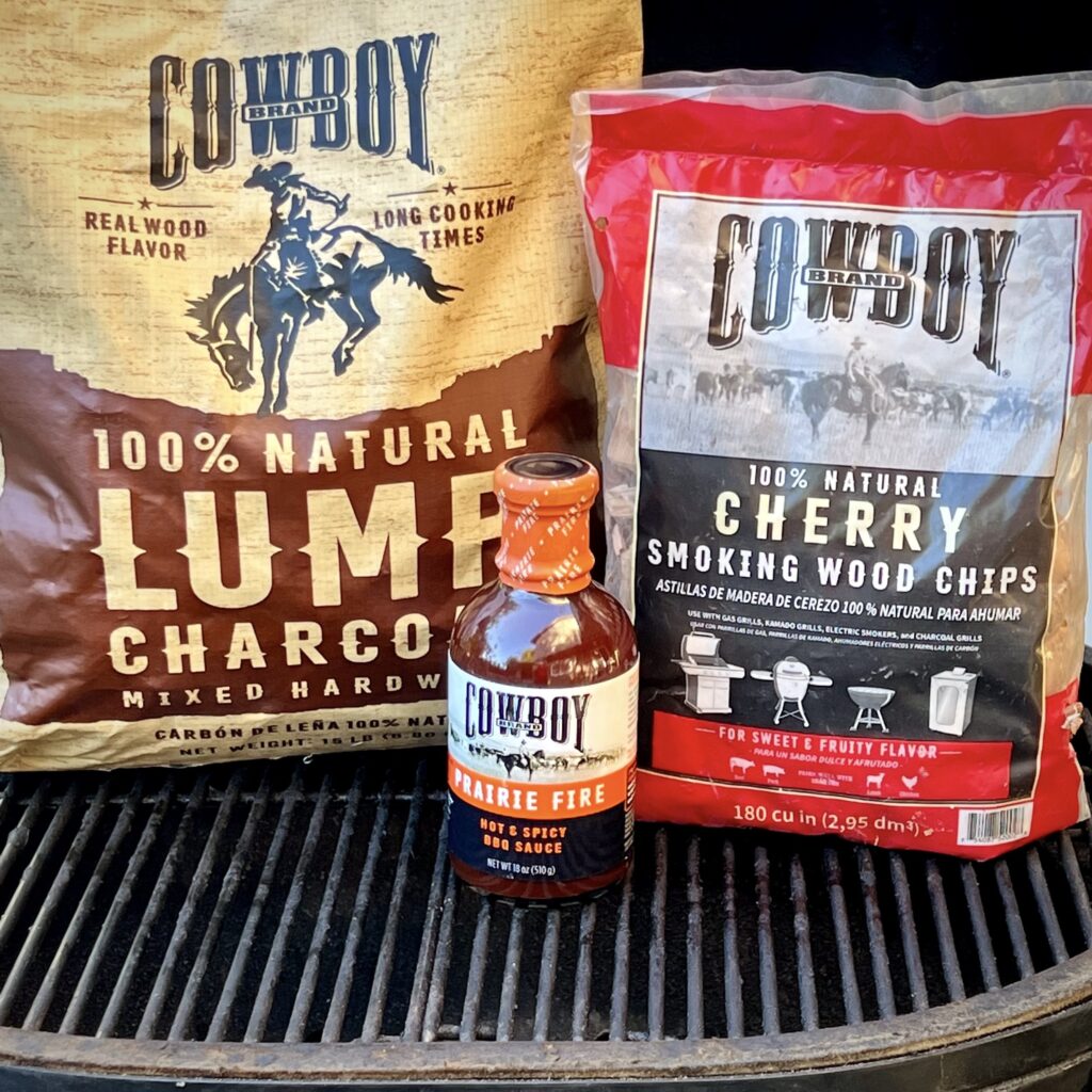 A bag of Cowboy Lump Charcoal, Cowboy BBQ Sauce and Cherry smoking chips. 