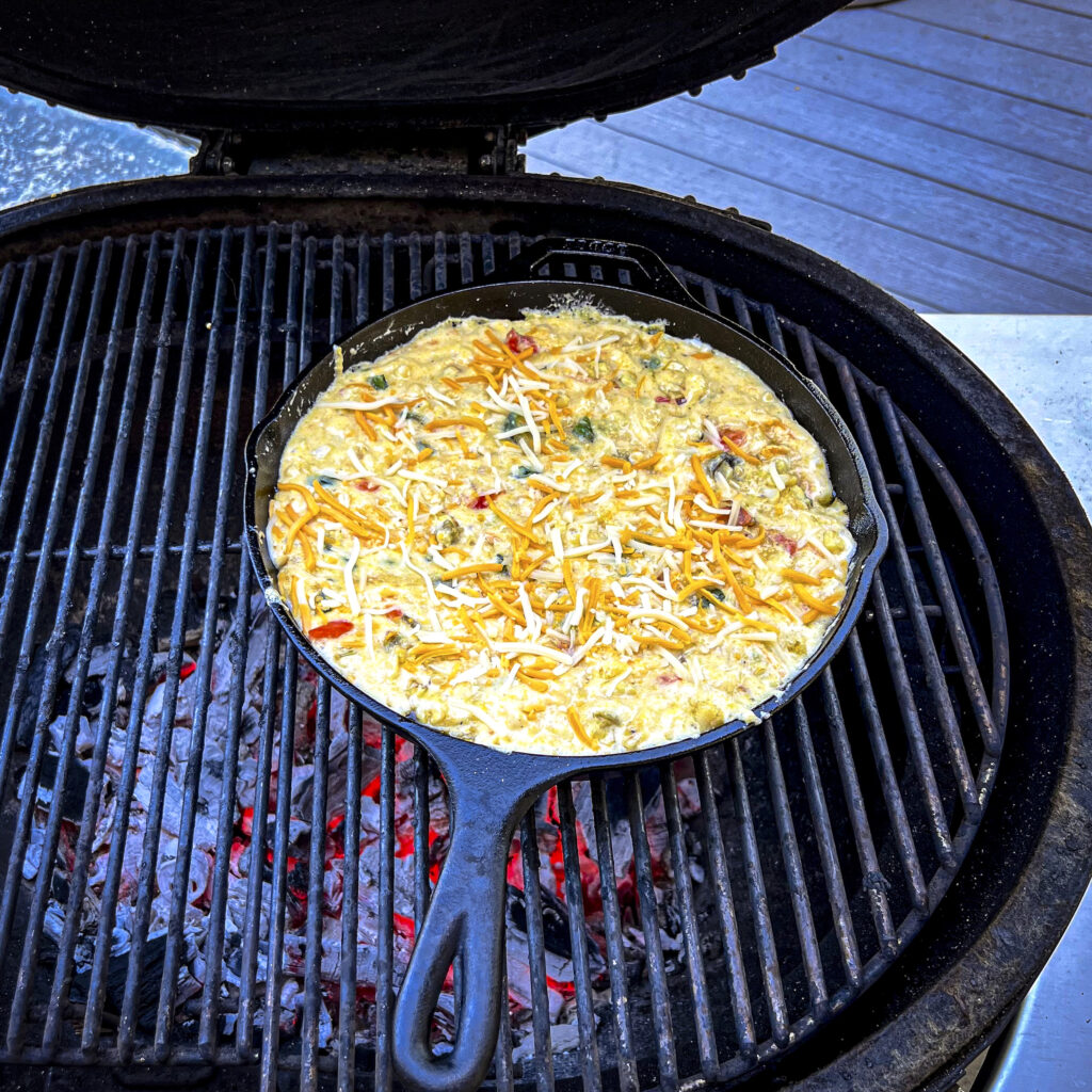A skillet on the grill with cornbread about to be baked. 