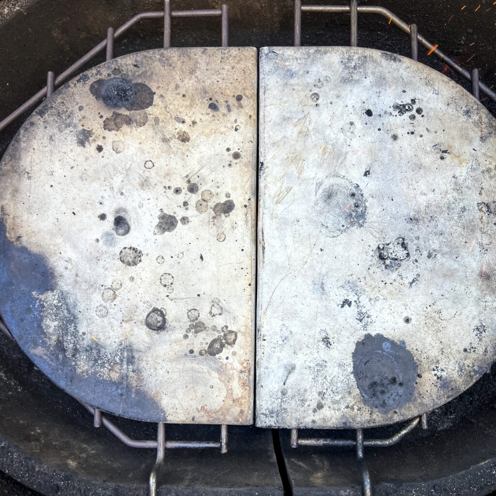 Two ceramic grill deflector plates are on a grill rack in a grill.