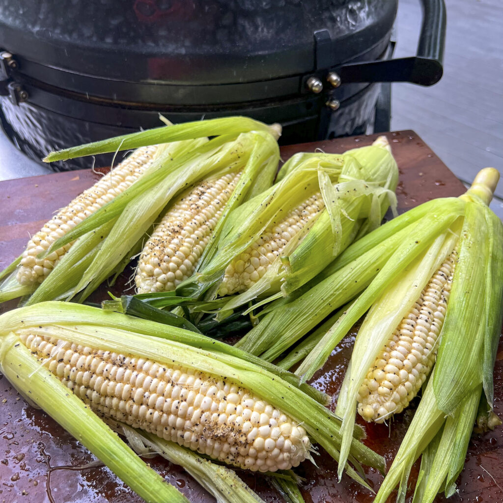 Corn has been seasoned and splashed in oil, and is now ready for the grill.