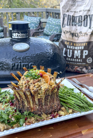 A Smoked Crown of Lamb sets in front of a grill and a bag of Cowboy Lump Charcoal.