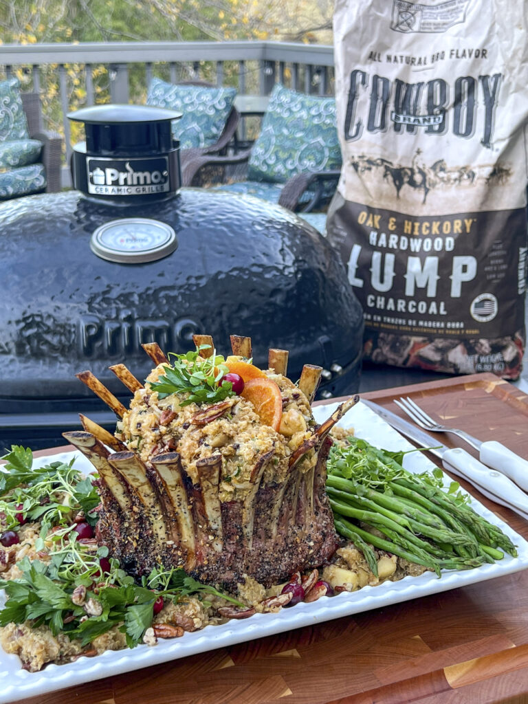 A Smoked Crown of Lamb sets in front of a grill and a bag of Cowboy Lump Charcoal.