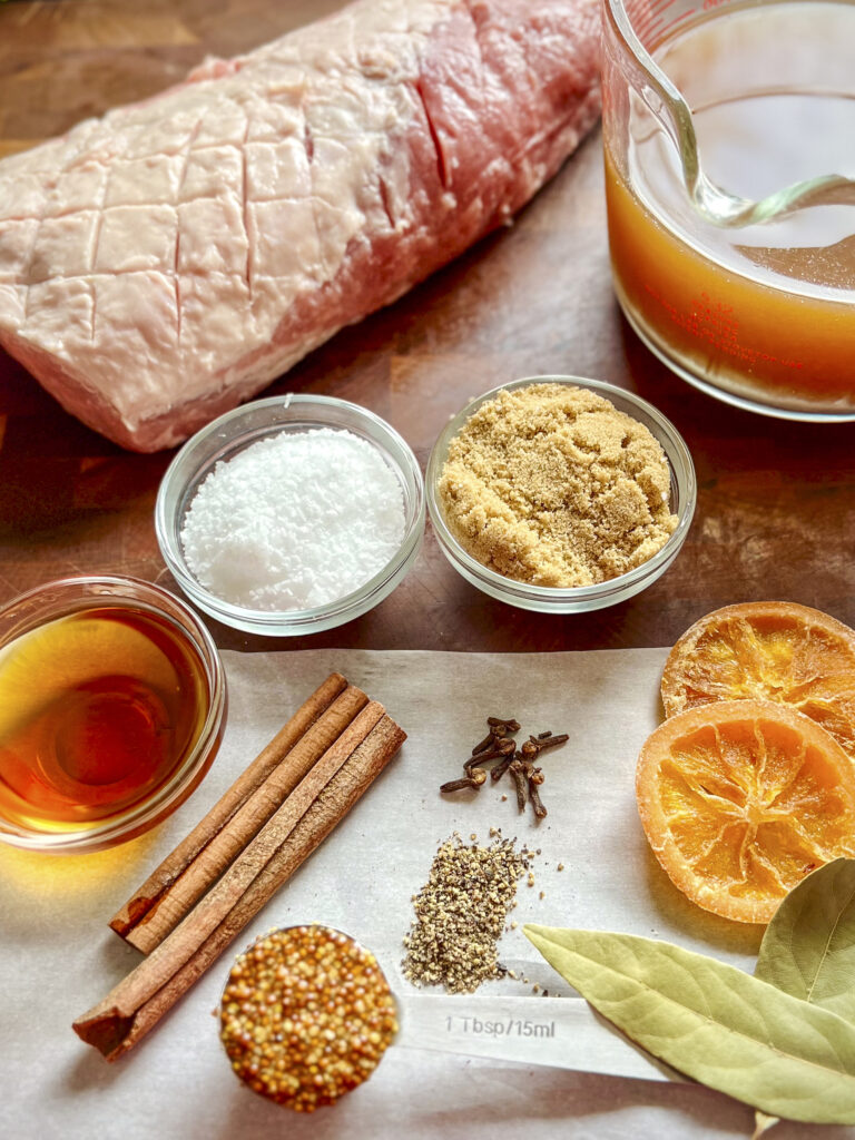 The ingredients for a apple cider with orange, cinnamon, cloves, and whiskey brine are shown.