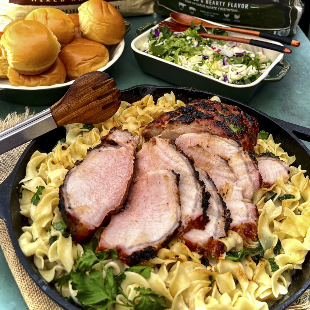Pork Loin is slices and on top of a bed of egg noodles with spinach. 