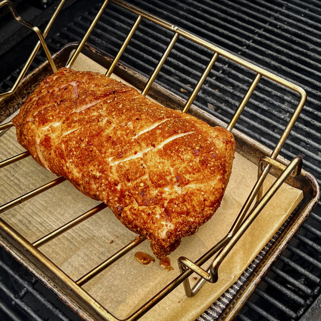 A pork loin is on a V-rack in the center of the grill. 