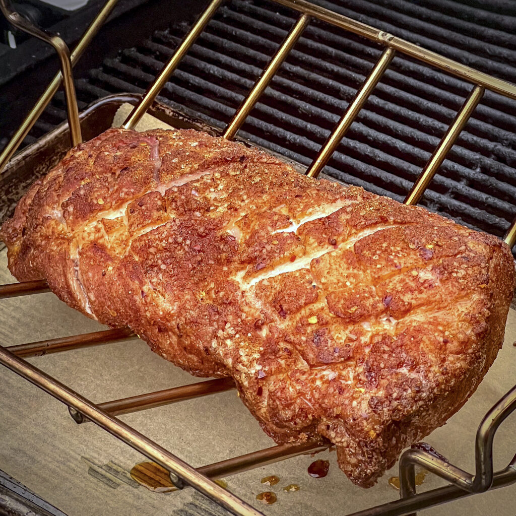 A partially smoked pork loin on a V-rack. 